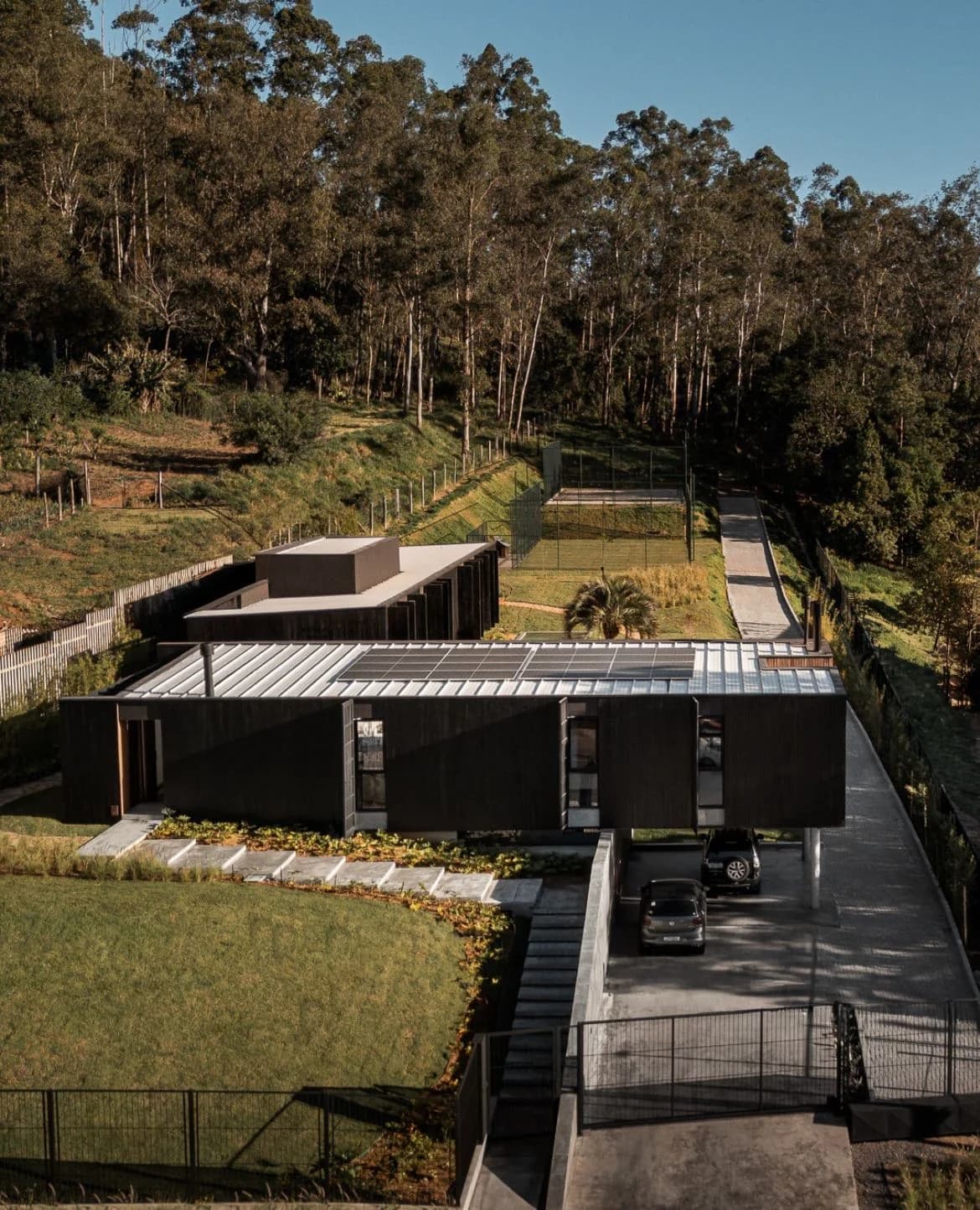 Casa Entremontes, volume em ripado escuro com a entrada iluminada